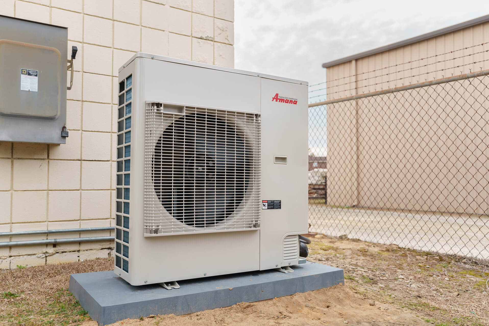 An Amana air conditioning unit installed outside of a building - Carolina Heating Service Inc. An Amana air conditioning unit installed outside of a building