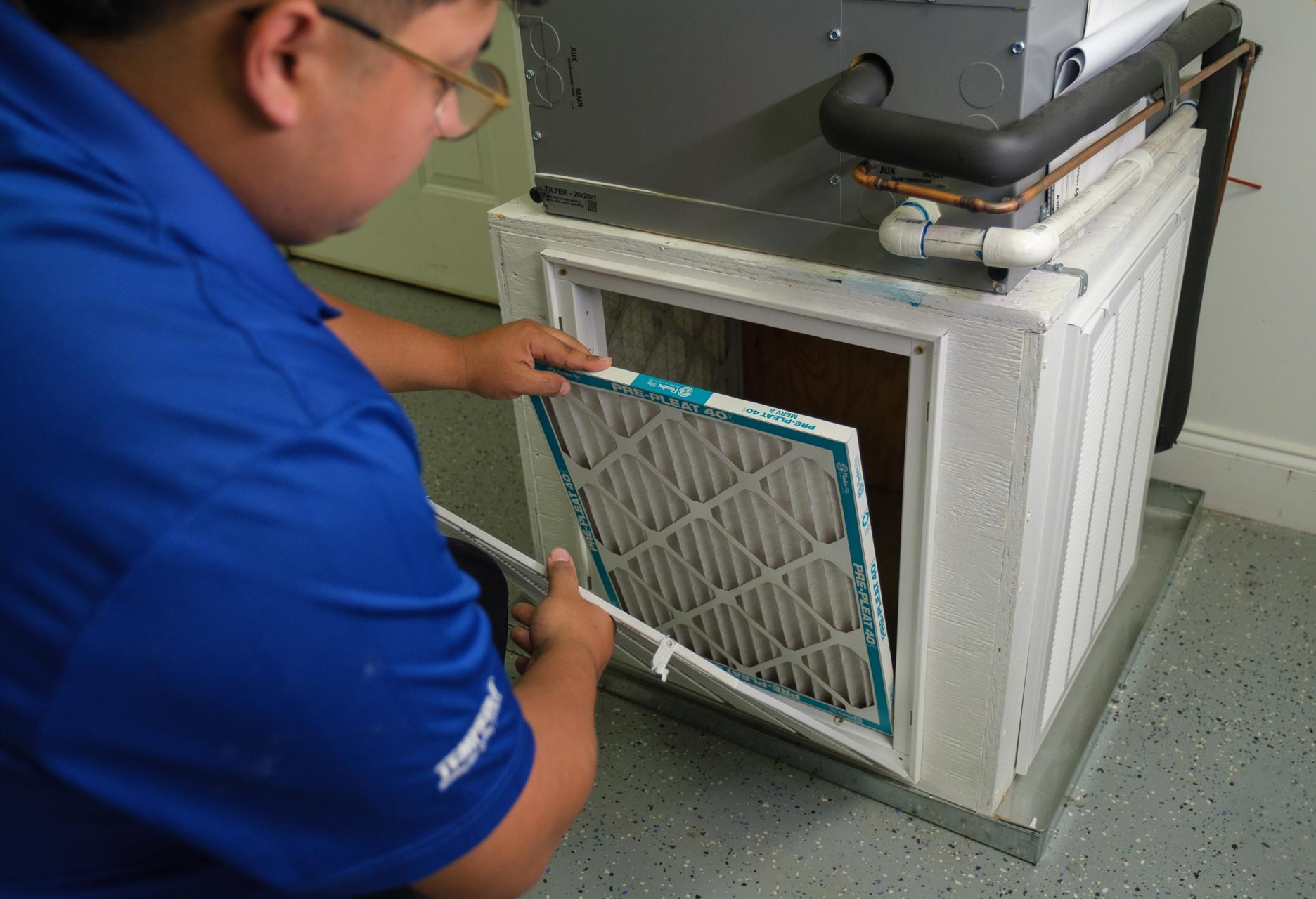 furnaces - Carolina Heating Service Inc. A technician replacing a filter on a gas furnace.