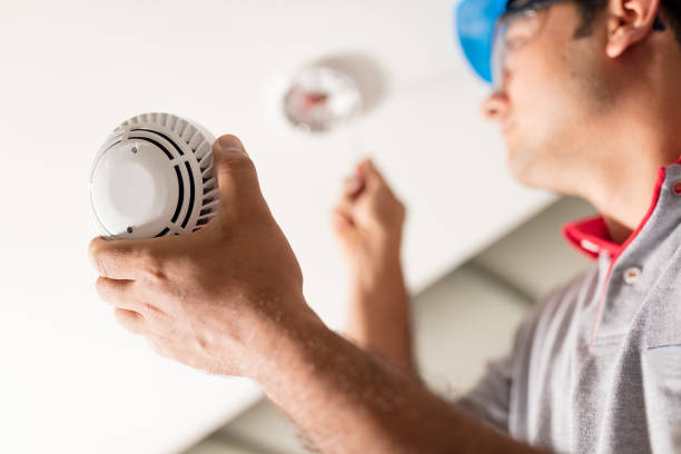 A licensed electrician installing a CO and smoke detector in Greenville, SC