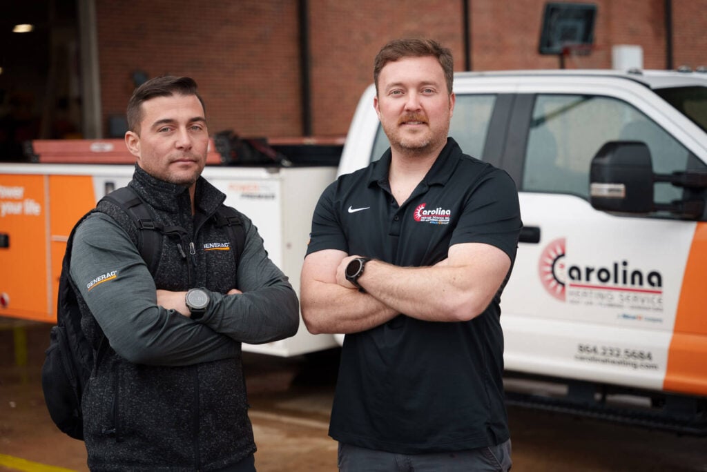 Two Carolina Heating Service technicians posing in front of a Carolina Heating Service truck - Carolina Heating Service Inc. Two Carolina Heating Service technicians posing in front of a Carolina Heating Service truck
